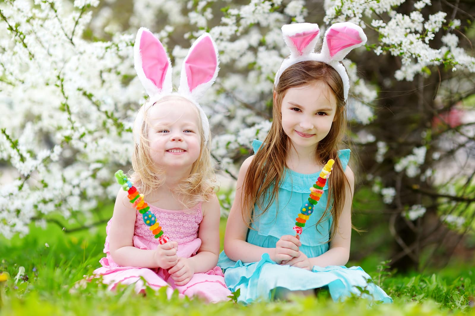 Two adorable little sisters eating colorful gum candies on Easte