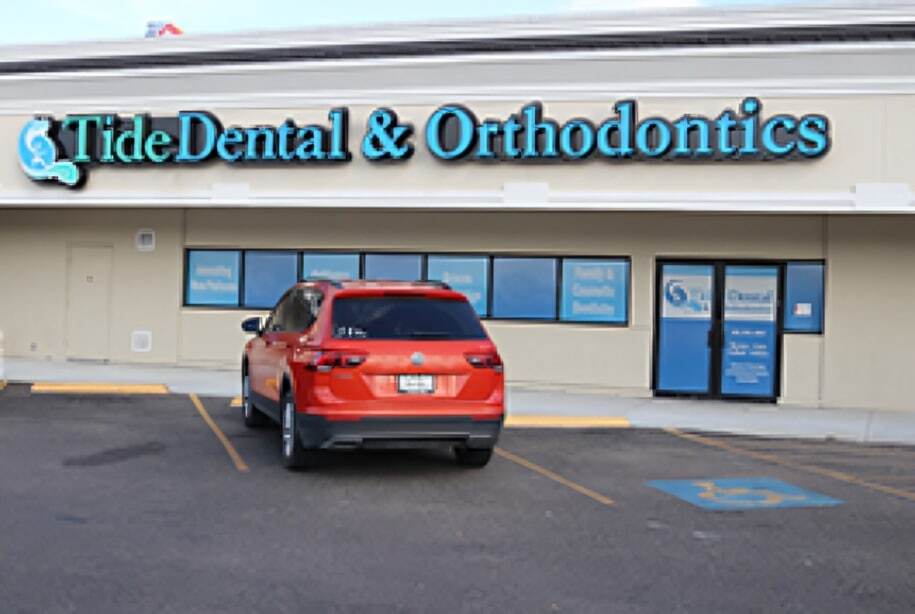 Red car parked in front of Tide Dental & Orthodontics storefront with blue entrance doors