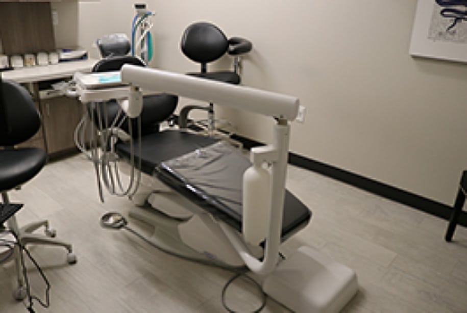 Dental treatment chair with overhead light and equipment in modern orthodontic clinic operatory.